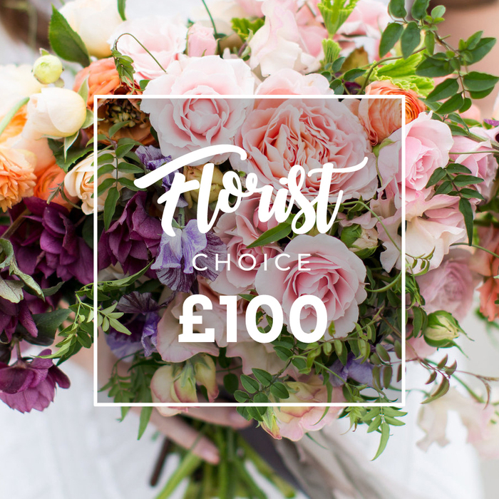 A sumptuous, hand-tied floral arrangement presented in an intimate, slightly elevated composition, overlaid by a neat white frame carrying the words Florist Choice in flowing script, CHOICE in smaller caps beneath, and a prominent ?100 in bold sans-serif at the lower edge - the visual shorthand of a premium, florist-selected option. The bouquet itself is a tapestry of texture and hue: multiple large garden roses in soft pink and blush unfold with densely petalled, velvety faces; clustered deep burgundy or plum hellebore-like blooms anchor the lower left with rich tonal weight; delicate striped sweet peas in pale lilac and white weave between stems, adding a fragrant, ethereal thread. Peach and coral ranunculus-style flowers introduce warm, radiant highlights while creamy white accents and tiny spray blooms create gentle punctuation. A generous layering of foliage - slender vines trailing slightly and broader, matte leaves - gives the design an organic, garden-gathered silhouette and enhances depth. The lighting is diffuse and natural, highlighting petal translucence and the layered shadows within each bloom. A pair of hands, with a faint white sleeve visible, clasps the neatly trimmed stems, signalling careful handling and artisanal presentation. As a local bouquet from Flower Delivery Stanmore, this image suggests thoughtful gifting for weddings, anniversaries or a meaningful sympathy tribute, evoking the scent of fresh-cut flowers and the calming green spaces of Stanmore Common and Bentley Priory nearby.