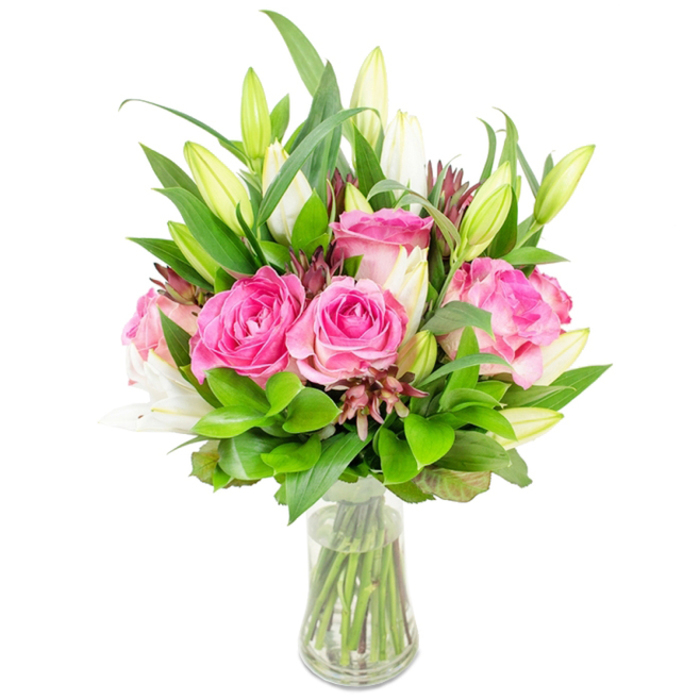 A radiant floral composition-rich pink roses paired with poised white lilies-rests in a clear glass vase against an immaculate white background, allowing each colour and texture to be read instantly. Multiple roses, fully open and lush, display layers of velvety petals in shades that move from delicate blush at the edges to a saturated fuchsia at the core; their round, soft forms anchor the arrangement with a romantic warmth. Rising among them are stately white lily buds, some kept tightly closed as graceful ovals, others just parting to show pale interiors and the promise of a fuller bloom; their vertical lines add elegance and a subtle olfactory freshness. Surrounding these focal blooms is a generous massing of greenery-larger pointed leaves add structure and darker tones, while smaller glossy leaves and wispy green sprigs introduce texture and movement. Throughout, hints of deep burgundy or reddish-brown filler elements are thoughtfully dispersed, creating contrast and a natural, garden-like complexity. The vase is transparent and classic in form, its slightly tapered base holding clear water through which the trimmed, healthy stems are visible, reinforcing the sense of recent cutting and careful care. The lighting is clean and bright, making the colours pop and casting a soft, flattering glow across petals and foliage-an effect reminiscent of early afternoon light in a Stanmore kitchen near Stanmore Hill. This bouquet reads as both celebratory and composed, suitable for special occasions like Mother's Day or an anniversary, or simply to bring a fresh, uplifting presence into a living room or dining table.