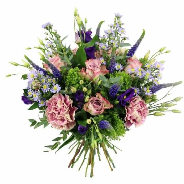 This image shows a richly detailed hand-tied bouquet set against a pure white background, allowing every petal, leaf and stem to stand out with clarity, much like a carefully curated arrangement in a Stanmore bay window catching soft afternoon light. The bouquet has a gently domed, rounded shape, overflowing with pink, mauve, purple and bright green. At the centre, pastel pink roses form the emotional core of the design: some buds are just beginning to open, while others spread out in full rosettes, revealing intricate spirals and petal edges that shift from a warmer pink inside to paler tones nearer the tips. Closely nestled among them are large, ruffled carnations in dusty rose and purple-mauve, whose layered frills bring volume, movement and an almost fabric-like richness. From within this soft sea of petals, slender stems of Veronica rise in deep lavender-blue, their tapering spikes giving height and lending a slightly contemporary flair to an otherwise classic bouquet. Threaded between the roses and carnations, luxurious lisianthus blooms in rich purple create pockets of deeper color and velvety texture, their bell-shaped flowers and tight buds suggesting quiet elegance. The arrangement is softened further by sprays of aster-style flowers, each tiny lavender or periwinkle bloom with a delicate yellow centre, creating a starry, mist-like effect that fills any small gaps. Encircling and weaving through the flowers, vivid chartreuse filler and cool, silvery eucalyptus leaves introduce varied shades of green, evoking the fresh, layered foliage of nearby gardens and the green spaces around Stanmore Hill. At the base, the clean-cut stems are gathered tightly by hand, showcasing the hand-tied craftsmanship. Photographed from a slightly elevated angle, the bouquet radiates a sense of thoughtful celebration, well suited to luxury flower delivery for birthdays, anniversaries or heartfelt thank-you gifts across Stanmore.