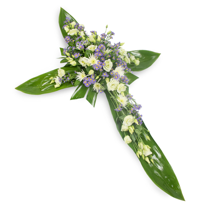 This heartfelt cross arrangement is composed with the care of an experienced florist, designed to read clearly from above and to convey consolation through form and colour. A foundation of rich, verdant tropical leaves-broad, glossy, and slightly veined-creates the defined horizontal and vertical arms of the cross, their smooth surfaces reflecting soft, even light. Crowning the centre and extending along each arm is a concentrated display of floral blooms in delicate white and creamy ivory, dominated by ruffled lisianthus whose multi-petalled heads bloom like small lanterns of calm. Nestled among them are compact white chrysanthemum-style flowers or spray roses, introducing bright points of texture and visual rhythm. Complementary sprays of tiny lavender or pale purple blossoms-limonium or similar asters-are sprinkled through the composition to give cool contrast and airy depth, while slender green filler stems weave through the clusters and unify the palette. The scent suggested by the image is faintly green and floral, subtle rather than heady, reinforcing the arrangement's meditative tone. Light falls evenly, lending a soft glow that enhances the gentle lavender accents alongside the creamy whites. In the Stanmore area, such a cross is often selected for memorial services at local churches or for laying at gravesides near Stanmore Common; it speaks of respect, steady compassion and quiet remembrance while remaining simple, refined and comforting.