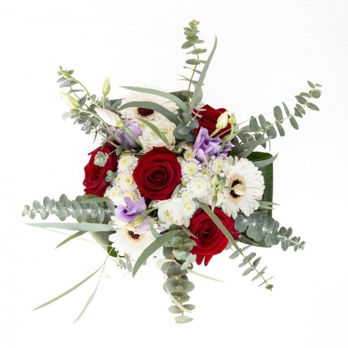From the perspective of a Stanmore florist, this arrangement stands out for its balanced composition and gentle elegance, much like the sense of calm found strolling near Stanmore Golf Course. The creamy white petals of gerbera daisies unfold from rich chocolate centers, grounding the bouquet as luminous anchors. Encircling these, classic deep-red roses, tightly spiraled and plush, evoke feelings of lasting affection and timeless sentiment-perfect for both romantic occasions and joyful gatherings. Overarching sprays of eucalyptus, their silvery-green leaves shimmering in the dappled light, bring movement and aromatic freshness, reminiscent of dew kissed mornings in Bernays Gardens. Intertwined among the main blooms, lilac lisianthus adds an unexpected whisper of modernity and charm, as if a gentle evening breeze carried color through the arrangement. Fluffy fillers in ivory and white cluster together, lending softness and dimension, while the bouquet's sturdy base features wide, gleaming greenery carefully wrapped for a refined touch-a hallmark of true Stanmore craftsmanship. The transparent vase showcases a lively tangle of stems, soaking in pristine water to keep every blossom vibrant. Altogether, the bouquet's air is inviting, serene, and seasonless-a versatile design suited for anniversaries, congratulatory gifts, or simply to bring a dash of natural artistry into a Stanmore living space.