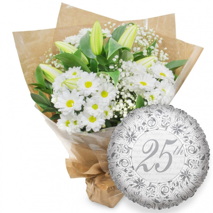 A classic silver anniversary arrangement is captured here: a lush white bouquet positioned next to a round silver foil balloon, all framed by a bright, neutral white background. The bouquet itself overflows with white chrysanthemum daisies, their crisp petals layered in tidy circles around bustling yellow centres that glow like soft candle flames. Interspersed among these daisies are slender white lily buds, standing tall and mostly closed, their tips brushed with pale green that hints at the creamy petals hidden within. Tiny flowers of white baby's breath weave between the larger blooms, creating a mist-like layer that softens the composition and lends a gentle, romantic mood. Surrounding the blossoms, deep green foliage arches outward, forming a natural frame that gives the arrangement balance and shape. The stems are gathered into a hand-tied bundle, sheathed first in clear cellophane that reflects a hint of light, then in rustic brown kraft paper with visible folds and soft crinkles, reminiscent of bespoke bouquets picked up from a friendly Stanmore florist after a stroll near Canons Park or along Marsh Lane. The base is neatly tied, ready to be carried to a family living room or set at the centre of a 25th anniversary table. To the lower right, partially overlapping the bouquet, rests a shimmering round silver foil balloon. Its lightly creased surface is adorned with intricate scrolling and stylised floral details in slightly darker silver tones, forming an ornate frame around the central 25th in flowing, grey script. Behind this focal text, the words Happy Anniversary repeat faintly in soft grey, like well-wishes murmured in the background. The harmonious pairing of clean white petals, verdant foliage and metallic silver accents perfectly reflects the timeless grace of a Silver Anniversary celebration in Stanmore.