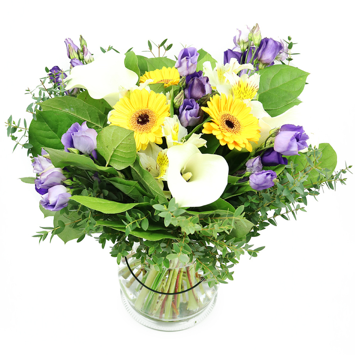 An elegant, sunlit bouquet sits in a clear glass cylindrical vase, photographed against a clean white background that lets every hue breathe. The dominant yellows of Gerbera daisies glow warmly, their round heads punctuated by dark centers that anchor the arrangement. Nestled between them are pristine white Calla lilies, their smooth, arching spaths tracing crisp lines through the bouquet. Soft lavender to purple Lisianthus provide a watercolor kiss of color, some open with ruffled rims, others still in bud, adding dimensional rhythm. Scattered white Alstroemeria with faint yellow streaks add delicate texture and lightness. A generous layer of greenery-the silvery eucalyptus with its pale, glistening leaves and broader emerald foliage-gives the arrangement vitality and a natural garden feel. The stems are neatly submerged in water within the glass vase, a visible testament to fresh-cut stems and careful preparation; a slender black tie inches above the water helps to hold the stems in perfect balance. The overall impression is one of buoyant freshness and refined joy, exactly the kind of bouquet you'd place in a Stanmore living room to celebrate a birthday, a milestone, or a heartfelt thank-you. Available for local delivery across Stanmore, reaching residents along the High Street, Northwick Park, and nearby lanes, often the same day. The design embodies the sense of neighbourly warmth that makes Stanmore feel like home, a thoughtful gesture you can send to a friend near Canons Park or as a bright welcome for a new arrival.