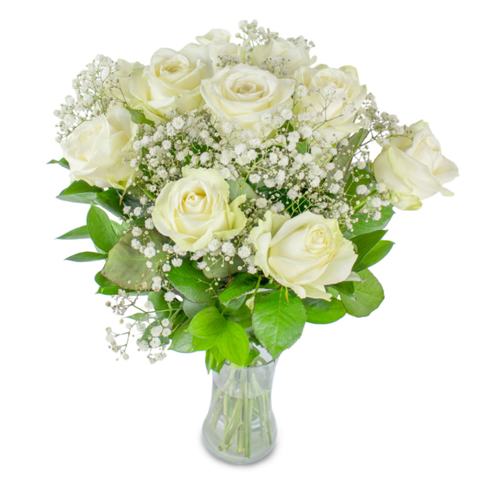 This bouquet reads like a study in quiet refinement: roughly a dozen pristine white roses, each petal edged in creamy translucence, set amid abundant baby's breath and glossy green foliage, arranged in a clear glass vase against an immaculate white backdrop. The roses are intentionally varied in openness-some fully blooming with layered, satiny petals, others still coiled toward the centre-which creates depth and a gentle visual cadence. Sprays of Gypsophila thread between and beyond the larger blooms, their tiniest blossoms resembling starlight or spun sugar and providing an airy, romantic veil that softens the composition. The greenery beneath provides structure and contrast, from rich, almost forest-hued leaves to brighter lime tones that lift the palette; together they ground the bouquet and emphasize the purity of the whites. The glass vessel exposes the trimmed stems and a clear water line, details that reflect the meticulous care taken by the florist and that signal readiness for delivery or display. The ambient illumination is soft and even, like light filtering through the trees at Canons Park, making the roses appear to breathe with a quiet life. The scent is subtle and fresh rather than overpowering, suited to moments of celebration, remembrance, or private tenderness. Imagined in Stanmore parlours or as a wedding table bloom at a nearby venue, this arrangement feels both ceremonial and intimately domestic-a composed expression of grace, calm, and thoughtful beauty.