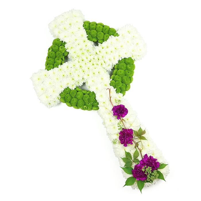 This photograph presents a striking Celtic cross floral tribute, carefully arranged and positioned diagonally across a clean white background so that its design stands out in full clarity. The cross's arms extend from the upper left to the lower right, giving a sense of gentle movement and guiding the eye along the tribute's length. The main form is constructed from numerous white chrysanthemum heads, each bloom small, round, and tightly packed. Together, they create a soft, tufted texture across the vertical and horizontal arms, evoking both comfort and reverence. Surrounding and threading through this white field, bright lime green button chrysanthemums highlight the classic Celtic ring and distinctive knotwork-like shapes. Their neat, spherical blooms and lively green colour carve crisp lines into the design, reminiscent of the fresh lawns and tree canopies found around Stanmore Hill and the paths near Canons Park. On the lower section of the vertical arm, three elegant clusters of deep purple carnations introduce a notes of solemn richness. The carnations' ruffled petals look velvety to the touch, unfolding in layers that deepen in tone toward the centre of each bloom. Delicate trails of dark green foliage, perhaps ivy or a similar climbing plant, weave among the purple flowers and extend slightly across the white chrysanthemum background, softening the rigid geometry of the cross and giving the impression of a natural vine resting on an old stone memorial. The lighting is bright yet gentle, revealing the freshness of the flowers and the fine detail in each petal without harsh glare. This Celtic cross arrangement, with its thoughtful combination of white, green, and purple, would serve as a deeply meaningful funeral tribute in Stanmore, offering a visual expression of faith, remembrance, and enduring love for a cherished family member or friend.