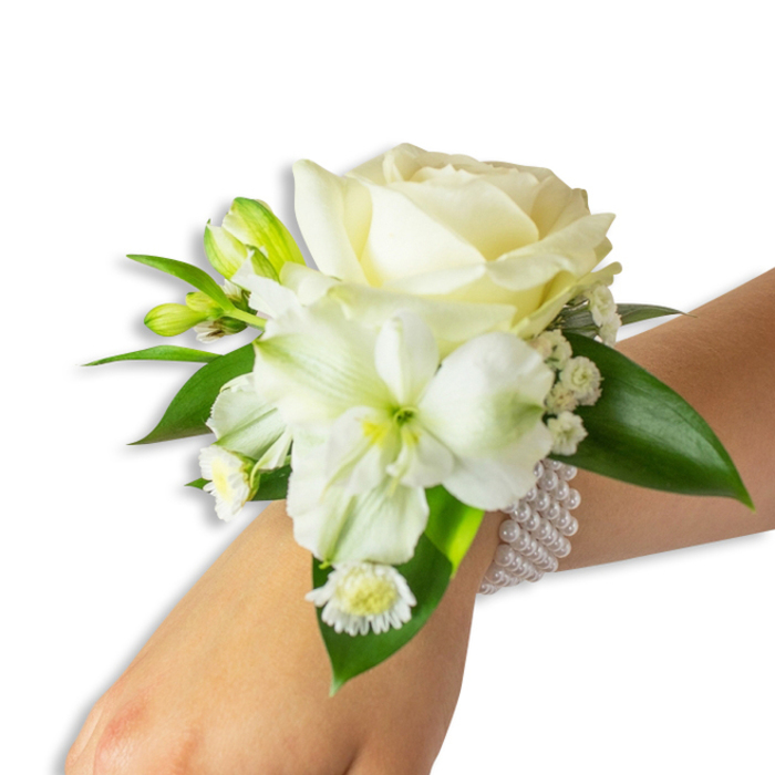 An elegant white wrist corsage photographed with a simple white backdrop so every texture and hue is clear: at the centre sits a creamy ivory rose, its petals unfurling in soft layers that catch the soft studio light and create a satin-like glow. Below and slightly offset is a larger, trumpet-shaped white bloom - likely a Peruvian alstroemeria or trumpet lily - its throat tinged with a fresh green-yellow that draws the eye inward and adds botanical complexity. Interspersed throughout are vibrant green buds, some still tight, suggesting new life and continuity, and delicate sprays of Baby's Breath (Gypsophila) that lend an ethereal, cloud-like softness to the silhouette. A small grouping of white, daisy-like florets with sunny yellow centres sits near the base, offering a charming, cottage-garden note among the refined blooms. The composition is anchored by several deep, glossy green leaves whose waxy sheen frames the white flowers and gives the corsage a lush, full appearance. Securing the piece is a tasteful multi-strand pearl band: uniformly round, luminous faux pearls wrap the wrist with understated luxury, their smooth coolness contrasting the warmth of the petals. As an item prepared for special occasions around Stanmore - from local weddings near Canons Park to school proms along Stanmore High Street - this corsage balances tradition and modern sensibility. Flower Delivery Stanmore designs and delivers similar pieces with careful wiring and fresh conditioning so the arrangement remains secure and fragrant throughout a day of vows and celebrations, evoking calm, timeless beauty in every gesture.