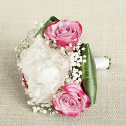 In this bouquet inspired by Stanmore's tranquil landscapes, classic pink roses intertwine with lush white peonies, creating a poetic balance of colour and texture. The roses display an ombre progression from magenta edges to a gentle blush and lavender centre, each spiral promising both freshness and elegance. Nestled among them, a voluminous white peony dominates the eye-its soft, intricate petals recalling the calm of early walks near Stanmore Hill. Wisps of gypsophila, or baby's breath, thread softly throughout, bringing an airy, whimsical beauty akin to morning mist. The sturdy base is formed by wide, glossy green leaves, skillfully wrapped to cradle the flowers and offer a pronounced contrast. A pure white satin ribbon secures the stems, the meticulous binding suggesting both artistry and occasion-perhaps crafted for a Stanmore wedding or heartfelt celebration. Set against a gentle, textured background and bathed in natural light, the arrangement feels at once cherished and timeless-ready to bring joy to any local moment of significance.