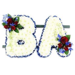 As a local florist in Stanmore, I often design personalised tributes like this pair of letter arrangements spelling BA, each letter entirely covered in hundreds of small, pristine white chrysanthemum heads that create a soft, cloud-like surface. The letters are edged with a wide royal blue satin ribbon, its ruffled texture sharply defining the shapes and adding a respectful, formal frame. A vivid cluster of deep red roses and spiky, electric-blue delphinium-like blooms sits on the upper left curve of the B; the A is balanced with a matching grouping at its lower right. Dark green foliage and pale green trailing tendrils weave through the clusters, bringing movement and a natural softness to the otherwise structured letters. Both initials are mounted side-by-side on a narrow dark green base that keeps the display freestanding and dignified against the plain white background. In gentle light the white chrysanthemums glow with quiet serenity while the velvety roses and blue accents provide focal points that read as love and remembrance. I prepare pieces like this for services at local venues around Canons Park, Stanmore Common, and nearby Harrow; Flower Delivery Stanmore can deliver these tributes across Stanmore and neighbouring communities for funeral, memorial, or commemorative events. The composition balances texture, colour and symbolism - the purity of white, the devotion of red, and the steady calm of blue - making it a personal, crafted farewell that comforts those who gather to remember a life.