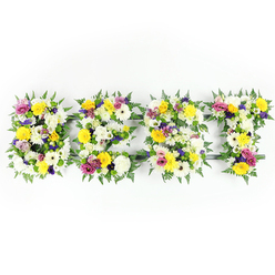 Presented head-on on a clean white field, this floral lettering spells BEST in generous, carefully packed forms that read clearly from a distance yet reward close looking with floral nuance. Each letter is a quilt of blooms: large white chrysanthemum-style flowers and ivory gerberas provide a calm, luminous foundation; interspersed sunny yellow roses and gerbera daisies bring warmth and an almost sunlit cheer; and soft purple lisianthus or small chrysanthemums add a gentle, contemplative depth. Bright magenta-pink spray roses or carnation clusters peek through, offering bright accents that lift the composition. Tiny clusters of pale green and white filler flowers knit the surface together, creating a tactile rhythm across the letters, while dark green fern fronds frame each character with a natural scalloped border. A discreet green framework can be seen through occasional gaps, especially near the horizontal bars of the E and T, a subtle reminder of the structural care behind such large designs. The lighting is even and fresh, emphasizing petal texture and the crisp contrast between blooms and background; one can almost imagine the soft rose scent and the clean green aroma of fern. This arrangement reads as a compassionate tribute - suitable for memorial services, funeral displays, or celebrations that honour a treasured person - combining florist craftsmanship with tender sentiment, a piece that comforts with colour and form in equal measure.