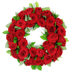 An elegant circular wreath of deep red roses rests before a clean white background, a testament to the artistry of a Stanmore florist. The ring is packed with dozens of blooms in varying stages of bloom, from tightly furled buds to fully opened petals, all sharing a velvety texture and a luxurious scarlet hue. The petals catch light in soft, nuanced gradations, creating depth and warmth that feels almost tangible. Intertwined among the roses are sprigs of fresh green foliage: broad, matte eucalyptus-like leaves provide a calm, muted green, while slender, glossy ruscus leaves punctuate with sharper accents. The result is a lush, three-dimensional circle whose edges shimmer with life, echoing the sentiment of eternal remembrance. Set against the white backdrop, the wreath radiates dignity, making it a poignant tribute for memorial services, anniversaries, or expressions of condolence. In the Stanmore area, these wreaths are frequently chosen to signal sympathy with grace, and they can be delivered locally to homes on Canons Park Road, through Stanmore's residential streets, or via same-day delivery across the district.