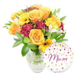 A cheerful, thoughtfully composed floral gift captured on a pure white backdrop, the bouquet resting in a clear glass vase that exposes neat, water-filled stems and the careful hand-trimming beneath. Large peachy-orange roses provide a warm, generous centre, their satiny petals curling outward with classic elegance, while bright yellow gerbera daisies scatter light across the arrangement with their flat, sunny faces and dark centres. Rich, burgundy carnations with tightly ruffled edges create a plush contrast and add visual weight, giving the composition a comforting, tactile quality. Small white alstroemeria blooms, faintly speckled, appear like delicate stars among the bolder flowers, lending a soft, sophisticated whisper to the palette. Varied green foliage-broad glossy leaves and slimmer sprigs-wraps the stems and lifts the arrangement, offering freshness and structure. A round white foil balloon sits to the bottom right, overlapping the vase slightly and decorated with playful gold and hot-pink confetti dots and tiny hearts; across its middle, the phrase best Mum is written in an elegant hot-pink script, a personal note that turns the bouquet into a heartfelt present. Picture this arriving on a quiet morning to a mum living near Canons Park or the quieter lanes off Roe Green; the mix of warm colours and gentle scent feels designed to brighten a kitchen table and bring an immediate smile.