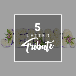 In this thoughtfully composed image, a personalised five-letter floral tribute rests on a pale, muted grey background, giving the eye space to appreciate each crafted detail. The letters are generously sized and freestanding, their surfaces densely covered with pristine white chrysanthemums. Every bloom is placed close to the next, creating a plush, even texture that brings to mind soft white clouds and conveys a sense of purity and peace, perfectly suited to quiet services around Stanmore, from local churches to chapels near Canons Park. Outlining each letter is a smooth band of deep purple satin ribbon, its rich tone offering gentle contrast and adding a dignified frame that makes the shapes easy to read, even from across a room. Here and there, the calm expanse of white is broken by small, carefully placed floral sprays: pale pink and lilac roses, some unfurling their petals, others still in bud, accompanied by light, feathery green ferns and other fresh foliage. These accents introduce subtle colour, depth, and natural movement, suggesting love, memory, and hope without disrupting the tribute's serenity. The partially visible sequence of letters hints at a name-"J" on the left, then "O," "H," and "N," with an "A" at the right-demonstrating how the design can be tailored to any five-letter name or meaningful word. At the centre, a slightly darker grey square overlay with a fine white border carries the wording "5 LETTER" in crisp white capitals above the word "Tribute" in graceful script, clearly indicating this as a bespoke funeral flower arrangement suitable for commemorating a loved one across Stanmore.