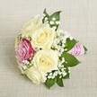 Laid upon a soft beige linen reminiscent of Stanmore's contemporary event settings, this petite bouquet reveals a harmonious blend of classic beauty and modern flair. Five creamy, pale roses form the lush foundation, their petals subtly illuminated to reveal intricate textures and depth. A single magenta-pink rose is positioned off-center, its rich hue providing an eye-catching focal point amid the gentle creams. Interspersed throughout are airy clusters of delicate, white baby's breath, lending a hint of purity and softness evocative of Stanmore's outdoor ceremonies and garden weddings. Deep green foliage edges the bouquet, offering a cool contrast and natural frame. The bouquet is held together by a vibrant pink satin ribbon, around which a string of glossy pearls spirals elegantly-each detail chosen with intention. Illuminated by diffused daylight and set against neutral linen, the bouquet radiates freshness and refined celebration. This arrangement is well suited to weddings, bridal parties, or marking a meaningful milestone in Stanmore, and stands as a testament to the local florist's careful artistry and attention to every heartfelt occasion.
