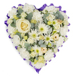 A tender, heart-shaped spray sits against a clean white backdrop, a quiet study in whites, creams and soft greens meant to comfort. At the center rests a single creamy white rose, its petals curling in a perfect spiral that catches a soft, almost morning-like light and draws the eye inward. Around that focal bloom, layers of ruffled white carnations offer gentle volume and a plush, tactile softness; their frilled edges form the rounded shoulders of the heart and invite a slow, reverent touch. Interspersed among the larger blooms are white spider chrysanthemums and small button-like daisies whose spidery petals and pale lime-green centres add a whisper of liveliness and fine texture. Scattered clusters of petite cream roses and budding lisianthus bring delicate points of interest, their tighter forms giving depth and the sense of moments held close.
Cool-toned sprigs of blue-green eucalyptus are tucked through the composition, their matte, coin-shaped leaves introducing muted contrast and a faint herbal scent that would lightly perfume a chapel or quiet home. The entire heart is edged with a deep lavender-to-rich purple ruffled ribbon, pleated into a scalloped frame that both defines the shape and lends a solemn, dignified accent. The careful placement of each bloom and leaf-densely layered yet airy where it needs to be-speaks to practiced hands and a mindful intention to convey enduring love, peace and respect. Imagined on a funeral easel or laid beside a casket, this arrangement reads as a gentle emblem of remembrance, suited to memorial services in Stanmore and the surrounding neighbourhoods, where families seek a composed, comforting floral tribute.