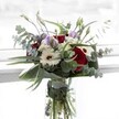This bouquet offers a graceful interplay of color and form-a blend of passionate red roses, creamy white gerberas, and dreamy lilac lisianthus, each carefully selected by florists in the heart of Stanmore. The fresh eucalyptus stretches outward, forming gentle arches that lend the arrangement an untamed elegance and capture hints of silvery green in the afternoon light, evocative of the shaded paths around Bentley Priory Nature Reserve. Sculptural dark green leaves cradle the flowers, their surface gleaming with vitality, while clusters of delicate, ivory filler blooms nestle among the more striking blossoms, adding a tactile softness that feels like a hidden treasure. The glass vase itself is unadorned, displaying vividly green stems immersed in clear, cool water, reinforcing the bouquet's impression of freshness and spontaneous beauty. The scent-a subtle mixture of rose and eucalyptus-is equally floral and refreshing, conjuring memories of joyful celebrations or quiet, thoughtful gestures shared in Stanmore homes. Designed to evoke gratitude, remembrance, and confidence, this composition cradles both emotion and artistry, marking moments worth cherishing across the local community.