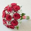 This exquisite bouquet, the centerpiece of many Stanmore weddings, radiates timeless elegance and heartfelt sophistication. A tightly rounded dome of vibrant, fully opened deep red roses forms the focus, each bloom lush, velvety, and brimming with intensity. Interwoven among the roses are feathery white clusters of baby's breath, giving the arrangement a light, cloud-like feel reminiscent of peaceful mornings in Stanmore's leafy neighborhoods. Dabs of dark green foliage peek between the blossoms, gently grounding the visual drama of red and white. The base is finished with an opulent red satin ribbon, accented by crisp white stripes and a glimmering swirl of delicate pearls-details as refined as the traditions celebrated in Stanmore's historic venues. Exposed green stems underline the bouquet's freshness and skilled local craftsmanship. Set against a softly textured pale background and illuminated by gentle, even light, every tone and texture is revealed in lifelike clarity. This bouquet, perfect for weddings, anniversaries, or romantic gestures across Stanmore, beautifully blends rich passion with pure affection-an enduring symbol of love locally grown and expertly arranged for life's most cherished moments.