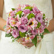 The image captures a hand-tied bouquet that radiates quiet joy and refined romance, as if prepared for a wedding or anniversary celebration in Stanmore's peaceful neighbourhoods. At the heart of the design, clusters of dusky mauve and lilac roses bloom in layered spirals, their petals velvety and cool, exuding an understated elegance that anchors the arrangement. Framing these roses, pink alstroemeria open with gentle flair, their elongated petals brushed with fine streaks of deeper pink and soft yellow, reminiscent of watercolour strokes and adding a sense of openness and movement to the bouquet. Nestled among them, delicate gypsophila forms airy veils of tiny white blossoms, filling the spaces between flowers with a soft, cloud-like texture that feels as light as whispered promises. Breaking through the pastels, bright green button chrysanthemums introduce playful pops of colour, their round, textured heads and crisp chartreuse shade giving the arrangement a modern, lively twist, similar to the fresh greens you might spot on a walk through Canons Park in early spring. A lush foundation of dark and mid-green foliage encircles the blooms, the leaves smooth and slightly glossy, bringing structure and harmony to the composition. The bouquet is bathed in soft, natural light, which accentuates the subtle shifts in rose colour and the detailed markings on the alstroemeria petals while keeping the overall mood calm and tender. It feels like the kind of bouquet chosen from a trusted Stanmore florist for same-day delivery to a local ceremony, a family gathering at home, or a special dinner, beautifully crafted to carry wishes for unity, joy, and lasting affection.