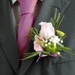 The understated luxury of this Stanmore boutonniere emanates from each floral detail, set against the backdrop of a crisply pressed charcoal suit and an exuberant magenta silk tie. The gentle blush of the pink rose at its centre immediately draws the eye, its velvet petals reminiscent of the first blooms in spring at Canons Park. Nestled beside, a pale pink alstroemeria - petals brushed with hints of plum and magenta - brings intricate charm and softness. Flurries of pure white baby's breath offer a touch of romance, while a tightly wound green chrysanthemum lights up the arrangement with spirited freshness. Subtle ferns and elongated green leaves add volume and a breezy texture that seems to dance in the light, capturing the ambience of Stanmore's elegant gardens. The stems are gathered and secured by a lustrous lavender satin ribbon, delicately tied and subtly reflecting the joyful pink of the wearer's tie beneath. This boutonniere is crafted for moments of distinction - weddings, proms, family celebrations - expertly reflecting the refined yet welcoming nature of Stanmore and serving as a final accent marking a day of love, unity, and tender memories.