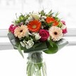 A tapestry of colour and texture bursts from this artfully constructed bouquet, echoing the cheerful spirit and lush surrounds of Stanmore. At its heart, warm peach gerberas radiate quietly, flanked by vivid orange peers that inject a spark of joy and celebration. Nestled between, lush magenta roses spiral elegantly, their deep hues invoking affection and shared memories-ideal for sending a meaningful message or enhancing a joyful milestone. Interspersed are crisp white alstroemeria and small filler blossoms, their light scent evoking mornings spent meandering through Stanmore's leafy avenues. Glossy aspidistra leaves wrap the arrangement in a protective, structured embrace, grounding the exuberant colours and providing a refined finish. The tall, clear vase displays the bouquet's lively green stems, a nod to freshly cut flora delivered across Stanmore's community. Sunlight filters gently through the background, illuminating every petal and leaf with warmth and subtle brilliance. This arrangement is a perfect way to express gratitude, delight in an achievement, or simply brighten the day of someone special in Stanmore.