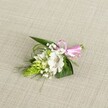 A delicately handcrafted boutonniere rests on a softly textured, light beige fabric, reminiscent of natural linen laid out on a dressing table in a Stanmore home before a special celebration. At its heart sits a single white alstroemeria blossom, the petals broad and gently ruffled, opening outward to reveal fine reddish-brown speckles concentrated near the throat and a cluster of pale stamens at the centre. To the left of this Peruvian lily rises a compact, conical cluster of lime-green buds, tightly packed like a miniature floral spike, adding an intriguing, sculptural contrast to the open bloom. Threaded between these focal elements, tiny clouds of white baby's breath drift through the design, their many miniature blossoms creating a misty, romantic softness. Surrounding and supporting the flowers is a careful mix of foliage: dark, sword-shaped leaves provide structure and depth, while finer, grass-like strands arc and curl with an easy, natural movement. The stems are neatly gathered and finished with a small, glossy satin ribbon bow in a clear, cheerful pink, tied to the right of the arrangement so the loops rest gently against the fabric. The lighting is even and calm, with no harsh shadows, allowing every vein, petal edge, and bead-like bud to be clearly seen, and giving the whole piece a feeling of freshness and quiet anticipation. This petite floral accessory, ideal for a lapel or wrist at a Stanmore wedding, prom, or anniversary dinner along The Broadway, conveys an intimate sense of celebration, as though prepared moments ago by a local florist attentive to each tiny detail.