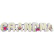 This image features a loving funeral tribute spelling out GRANDMA in bold yet gentle floral letters, each formed from densely packed white chrysanthemums that create a soft, velvety landscape of petals. The chrysanthemums' pure white tone brings a sense of calm and reverence, while a narrow band of pale lilac ribbon delicately frames each letter, lending refinement and a touch of soothing colour. At several points along the tribute, especially near the first and last letters, sit small, gathered clusters of pink gerbera daisies and pink roses, interwoven with sprigs of fresh green foliage. These accent posies add lively pops of colour and natural texture, echoing warm memories and moments of joy within the stillness of farewell. The light falls evenly over the arrangement, making the whites gleam softly and the pinks glow with gentle warmth, without any harsh shadows. This is the sort of carefully composed tribute you might see delivered to a Stanmore funeral service, perhaps placed with care near the front of a church or a quiet room at the crematorium, where family and friends can reflect. Every element-from the tidy chrysanthemum coverage to the graceful ribbon edge-reflects the skill of a professional florist serving the Stanmore area. The overall feeling is one of peace, dignity, and deep affection, allowing the flowers to speak quietly on behalf of those who loved their grandmother so dearly.