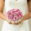 From the first glance, this Stanmore bridal bouquet radiates a delicate tension-vivid, generous roses swirling in gradients of blush and magenta, their soft petals entwined with airy sprigs of white gypsophila. This floral harmony is lovingly nestled against the chest of a bride, her skin lightly kissed by sunshine and her nails painted a shy, pearlescent hue. Her sleeveless wedding gown, rich with detailed floral lace across the bodice, gracefully tapers into a gentle V-neck and a sash that flows with movement unique to Stanmore's storied wedding venues. The background-muted and softly blurred-ensures full attention to the entwined textures of lace, skin, and florals, evoking feelings of hope and quiet joy. There is a subtle fragrance to the scene, imagined from the roses and baby's breath, bringing to mind fresh bouquets gathered from Stanmore's local flower markets. The bouquet stands as a symbol of eternal promise-a scene that transcends ornament to become part of a lifelong memory rooted in the community's heart.