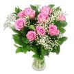 A delicate yet abundant arrangement of pink roses and baby's breath is displayed in a clear glass vase against a pure white background, capturing the calm sweetness of baby celebrations in Stanmore. The bouquet forms a rounded, harmonious shape with about a dozen pink roses at its centre. Each rose shows layers of soft, velvety petals that gradually deepen in colour from a pale, almost cotton-candy pink at the outer edges to a richer, rosy tone near the middle. Some flowers are fully open, revealing the intricate swirl of petals at their hearts, while others are at an earlier stage of bloom, still cupping their centres like tiny secrets, echoing the tender vulnerability of a newborn. Interwoven through the roses are fine, branching stems of white Gypsophila, known as baby's breath, whose countless miniature blossoms create bouncy, cloud-like clusters that add lightness and gentle volume. A frame of lush dark green foliage surrounds the flowers, the leaves firm and slightly glossy, emphasizing the contrast between the vivid greens and the soft pink and white blossoms. The stems are arranged neatly in a straightforward clear glass vase, partially filled with water, where the straight, green stems can be seen clearly, underscoring the sense of freshness and professional floristry. The bright, evenly distributed lighting eliminates harsh shadows, instead offering subtle highlights along each petal and on the surface of the glass. This classic pink-and-white bouquet feels perfect for welcoming a baby girl in Stanmore, delivering warm wishes to families near Canons Park, quiet cul-de-sacs off The Common, or any home where a new little life is being celebrated.