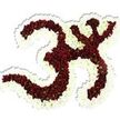 A sculptural floral tribute shaped precisely into the sacred Om (Aum) symbol rests against a pure white studio background, the clarity of the backdrop making every petal and curve instantly readable. The symbol's main body is formed from thousands of tiny, deep maroon to burgundy chrysanthemum-like blooms, each with a subtle lime-green eye that gives the mass of red a natural, living texture. Around those rich red forms, a thick undulating border of pristine white spray chrysanthemums crisply defines the Om's loops, the crescent and the little bindu above, so the sacred contours read clearly even from a distance. The flowers are packed densely and sculpted to a lush, slightly domed surface; the petals suggest a cool, silky touch and a soft, velvety visual weight. Studio lighting casts a gentle drop shadow beneath the piece, emphasizing its three-dimensional presence as though it might be lifted from the page. There is a faint, earthy perfume of fresh chrysanthemums-quiet and grounding rather than overpowering-that would suit a temple hall, meditation circle, or a reverent memorial setting. As a local florist familiar with Stanmore's community events around Canons Park and Stanmore High Street, I imagine this arrangement placed at a cultural celebration, a yoga retreat, or beside a shrine during quiet remembrance. The craftsmanship is deliberate and reverent: each tiny bloom chosen for colour consistency, each white outline placed to honour the symbol's balance. Visually and emotionally the piece reads as devotion made floral-serene, precise, and deeply respectful-carrying a calm presence appropriate to spiritual gatherings and commemorations in and around Stanmore.
