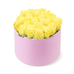 An elegant floral hat box, filled to the brim with yellow roses, is presented against a crisp white backdrop, allowing its refined details to shine-much like the quiet elegance of Stanmore's tree-lined streets. The box itself is round and pastel pink, with a soft, matte finish that evokes the feel of a velvety or suede-like material, reinforcing the sense of a premium, carefully curated gift. Rising above the rim, approximately two dozen yellow roses form a gently domed crown, their heads packed closely so that you see almost nothing but petal upon petal. Each blossom is at its peak, with velvety petals unfolding from softly shaded, creamy centres into more vivid lemon and golden hues at the edges. Subtle touches of green foliage are threaded between some of the roses, providing a delicate contrast that keeps the design lively and natural. The lighting is even and diffused, revealing the intricate textures of the petals and the smooth surface of the box, while eliminating any distracting shadows. Visually, the piece gives a feeling of joyful sophistication-perfect for a birthday surprise delivered to a home near Stanmore Golf Club, a congratulatory gesture after an exam success, or a simple message of friendship sent to someone in Belmont or Canons Park. This arrangement captures the warmth and optimism of yellow roses in a modern presentation that would sit beautifully on a dining table, coffee table, or hallway console, bringing a moment of sunshine into any Stanmore home.