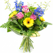 A colourful bouquet of fresh flowers stands proudly against a plain white background, every bloom clearly defined and thoughtfully placed, evoking the careful work of a Stanmore florist. At the centre, open pink roses display soft, velvety petals that curl back gently, layering from a slightly deeper rose at the heart to a softer blush on the outer edges, suggesting tenderness and affection. Around them, yellow gerbera daisies with deep brown centres form bright circles of sunshine, their flat, daisy-like faces and delicate, ray-like petals imbuing the arrangement with a sense of happiness and easy charm, much like a sunny afternoon wandering the shops near Stanmore Broadway. Tall spikes of rich blue delphinium rise from the middle of the bouquet, adding height and a cool, striking contrast to the warmer tones. Each spike carries numerous small, open flowers that step upward along the stem, creating a ladder of colour and giving the bouquet a graceful, slightly formal line. The spaces between the main blooms are filled with varied greenery: light, feathery fern fronds spill gently from the edges, while large, glossy leaves curve around the lower section of the arrangement to form a neat, sculpted collar, with some leaves displaying subtle pale striping that catches any available light. Tucked among the flowers, bright green, textured filler foliage creates a plush, cushion-like background that enhances the bouquet's full, rounded silhouette. Slender stems topped with tiny buds emerge delicately from the top, adding a sense of new life and movement. At the bottom, the natural stems are gathered together and wrapped in soft cream or pale green material, tied simply, ready for delivery as a cheerful thank-you, a get-well gesture, or a birthday surprise to homes around HA7 and the leafy edges of Stanmore Country Park.